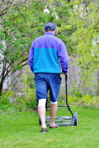 man mowing with a reel lawn mower