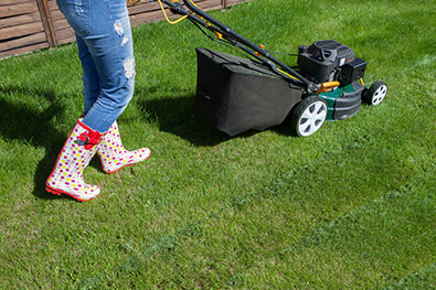 woman walking behind a lawn mower