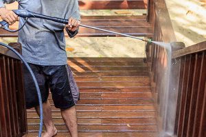 man pressure washing a deck