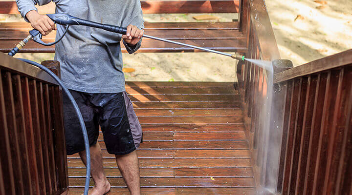 man pressure washing a deck