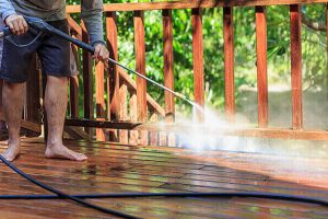 man pressure washing a deck