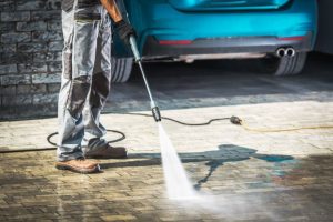 Man pressure cleaning driveway