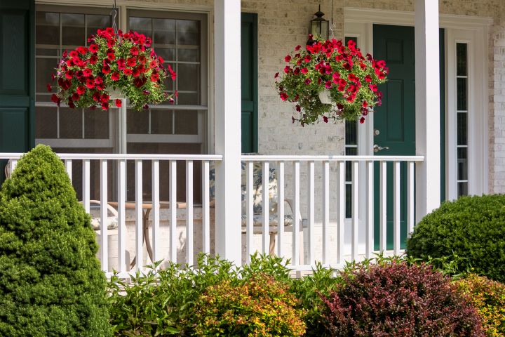 red flowers in hanging baskets on porch