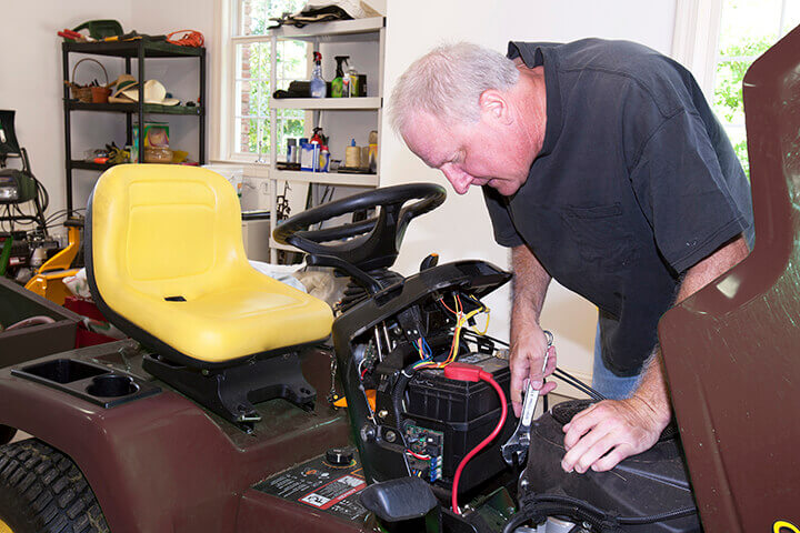 man working on a riding lawn mower