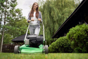 Young woman cutting grass with a lawn mower