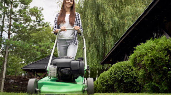 Young woman cutting grass with a lawn mower